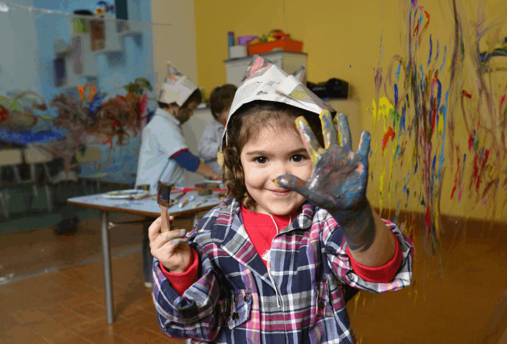 Das Bild zeigt ein Kind, wie es selbstbewusst eine angemalte Hand ausstreckt.